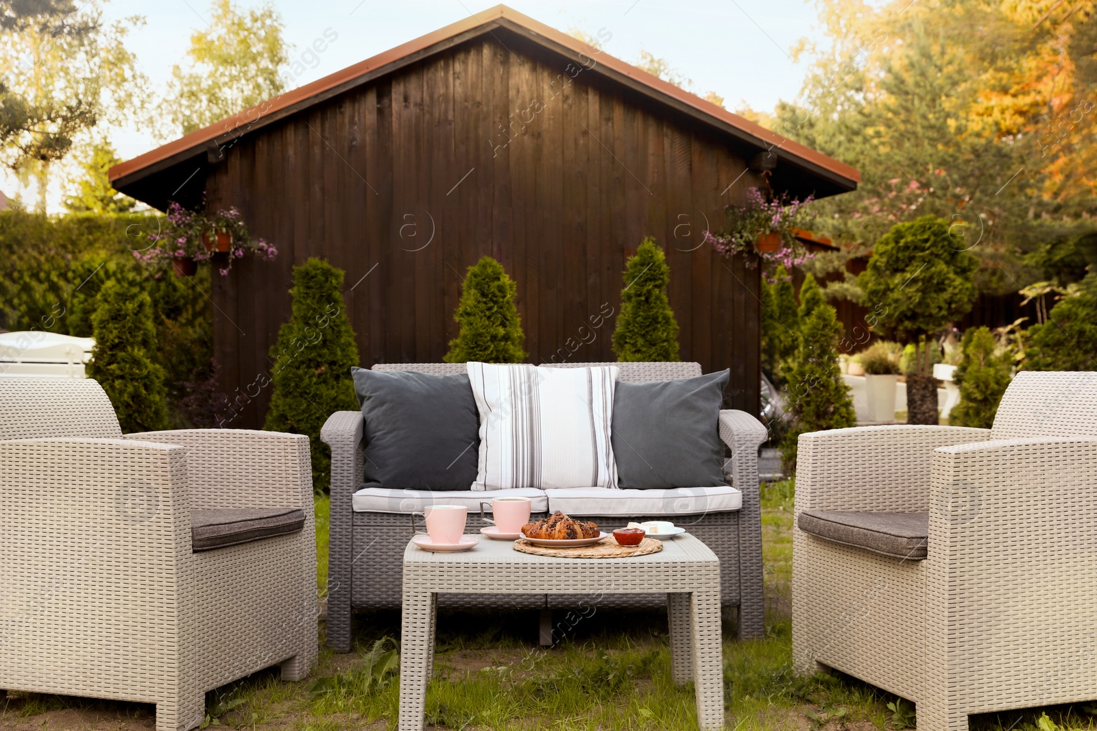 Outdoor breakfast with tea and croissants on rattan table in garden Photo of Outdoor breakfast with tea and croissants on rattan table in garden