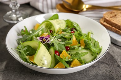 Photo of Delicious salad with cucumber and orange slices on gray table