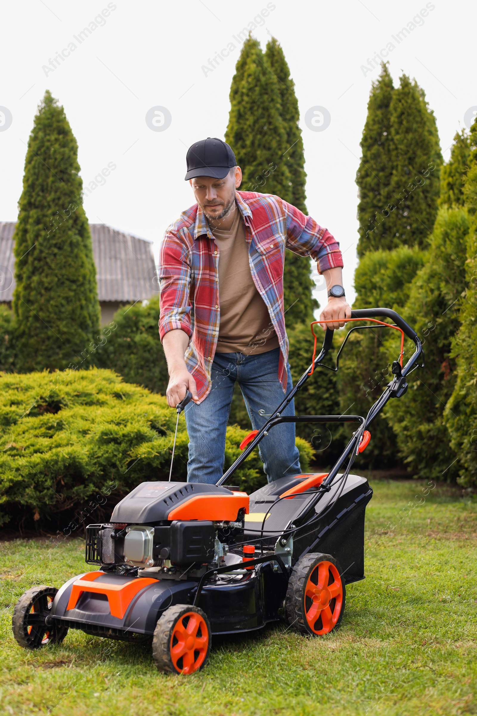 Photo of Man with modern lawn mower in garden
