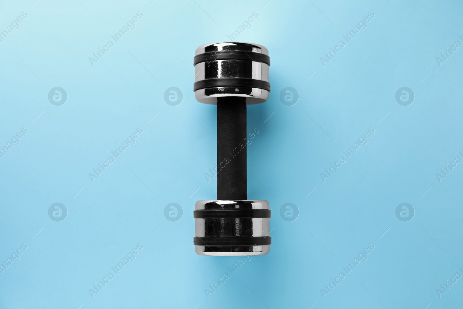 Photo of Stylish dumbbell on light blue background, top view