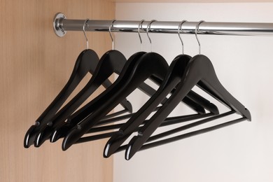 Photo of Set of black clothes hangers on wardrobe rail