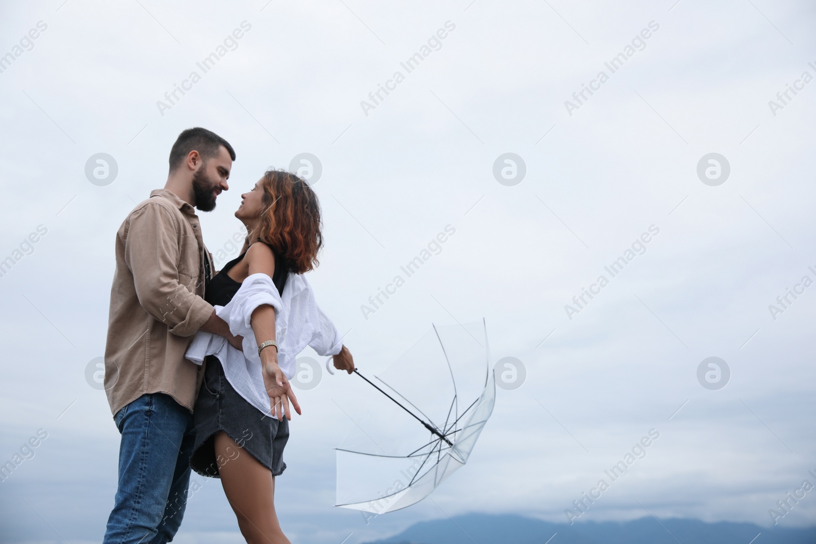Photo of Young couple with umbrella enjoying time together under rain outdoors, space for text