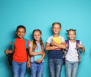 Photo of Group of little children with backpacks and school supplies on color background