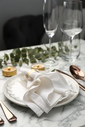 Beautiful place setting with candles and eucalyptus on white marble table