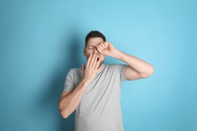 Photo of Portrait of sleepy man yawning on turquoise background