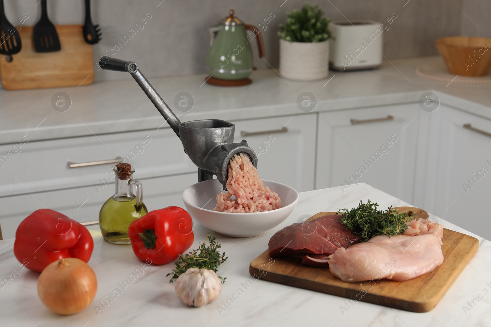 Photo of Metal meat grinder with chicken mince and products on white marble table in kitchen