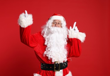 Merry Christmas. Santa Claus in headphones pointing at something on red background