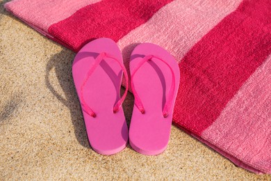 Photo of Beach towel and stylish slippers on sand