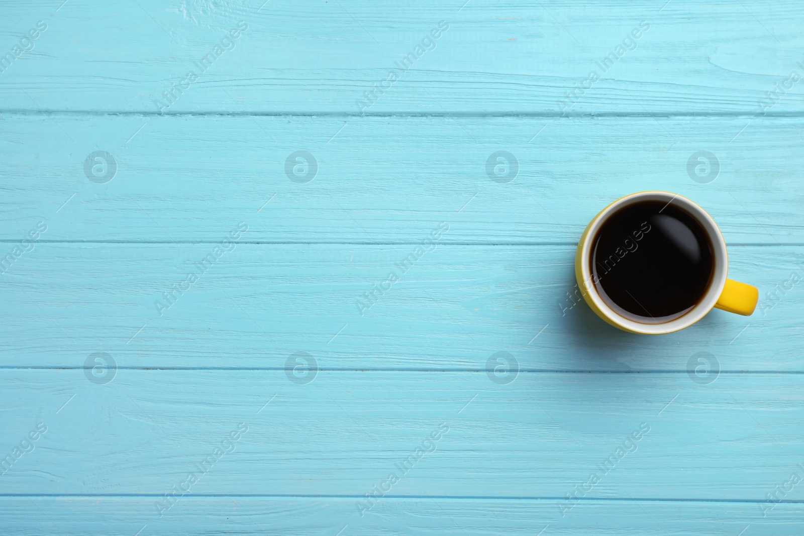 Photo of Ceramic cup with hot aromatic coffee on wooden background, top view