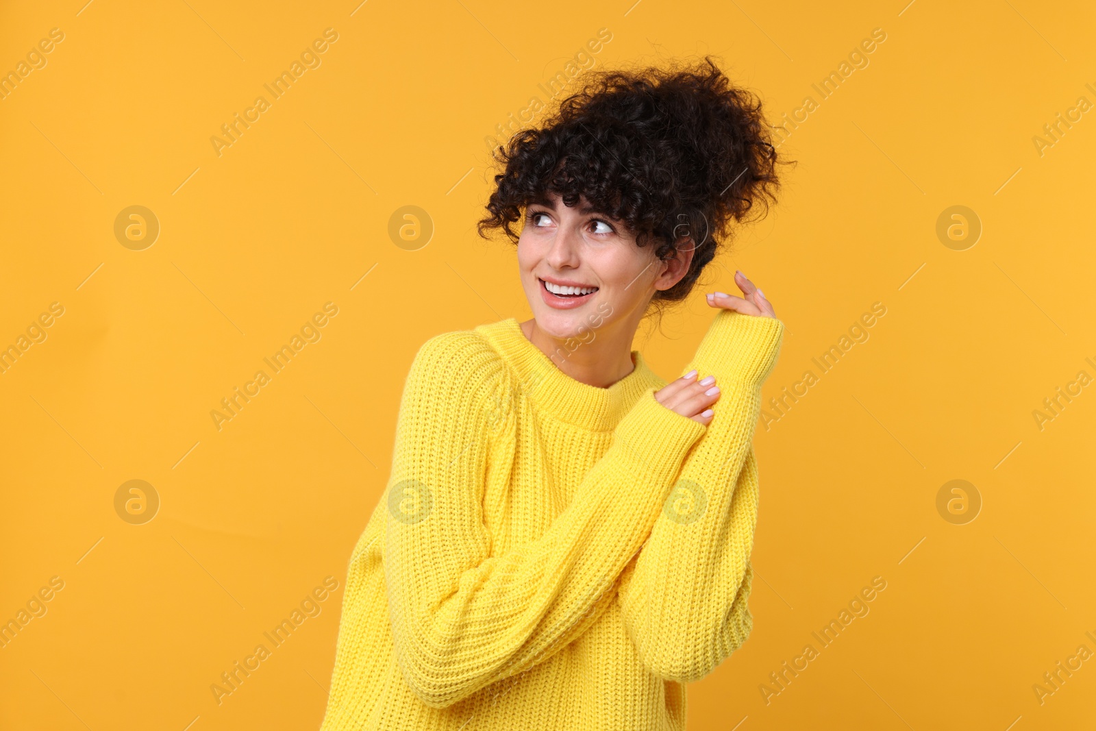 Photo of Happy young woman in stylish warm sweater on yellow background