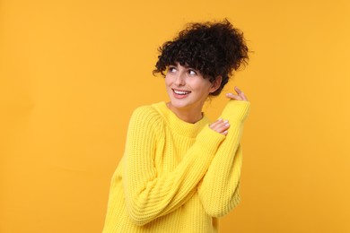 Happy young woman in stylish warm sweater on yellow background