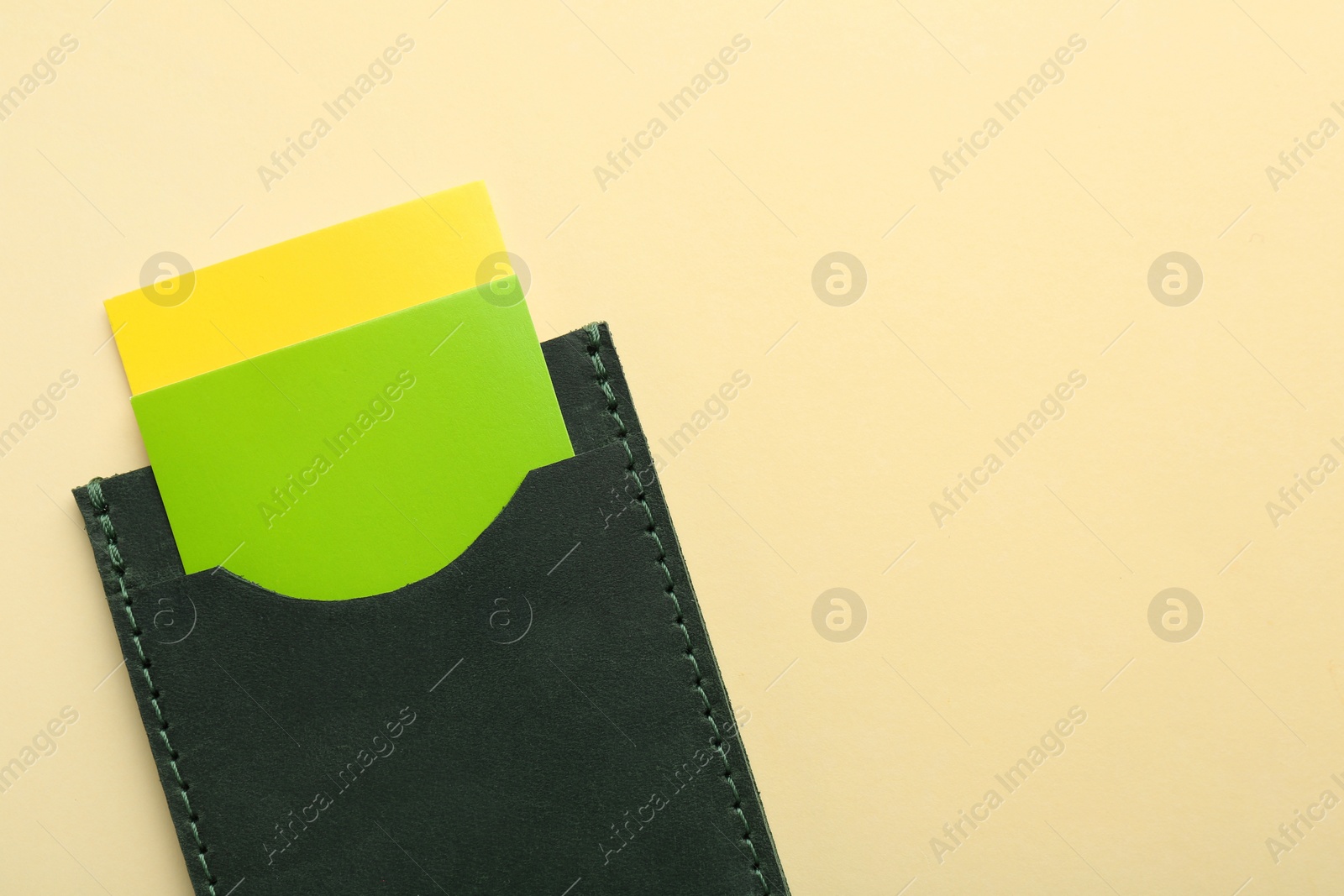 Photo of Leather business card holder with colorful cards on beige background, top view. Space for text