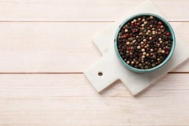 Photo of Aromatic spices. Different peppers in bowl on wooden table, top view. Space for text