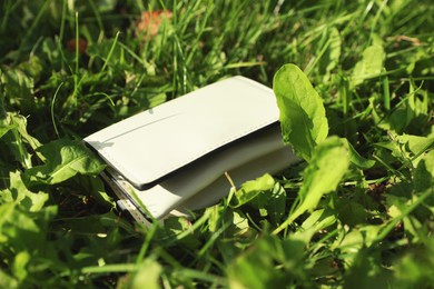 Photo of White leather purse on green grass outdoors, closeup. Lost and found