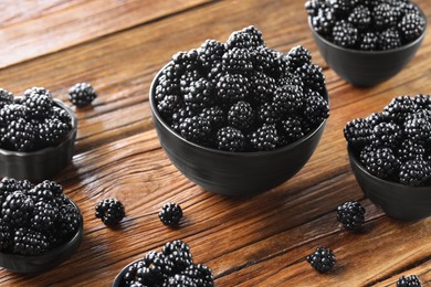 Ripe blackberries in bowls on wooden table
