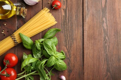 Photo of Raw pasta, spices and products on wooden table, flat lay. Space for text