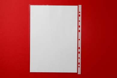 Punched pocket with paper sheet on red background, top view