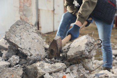 Man breaking stones with sledgehammer outdoors, closeup