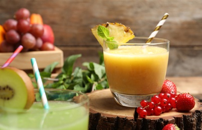 Photo of Delicious colorful juice in glass and fresh ingredients on wooden table, closeup