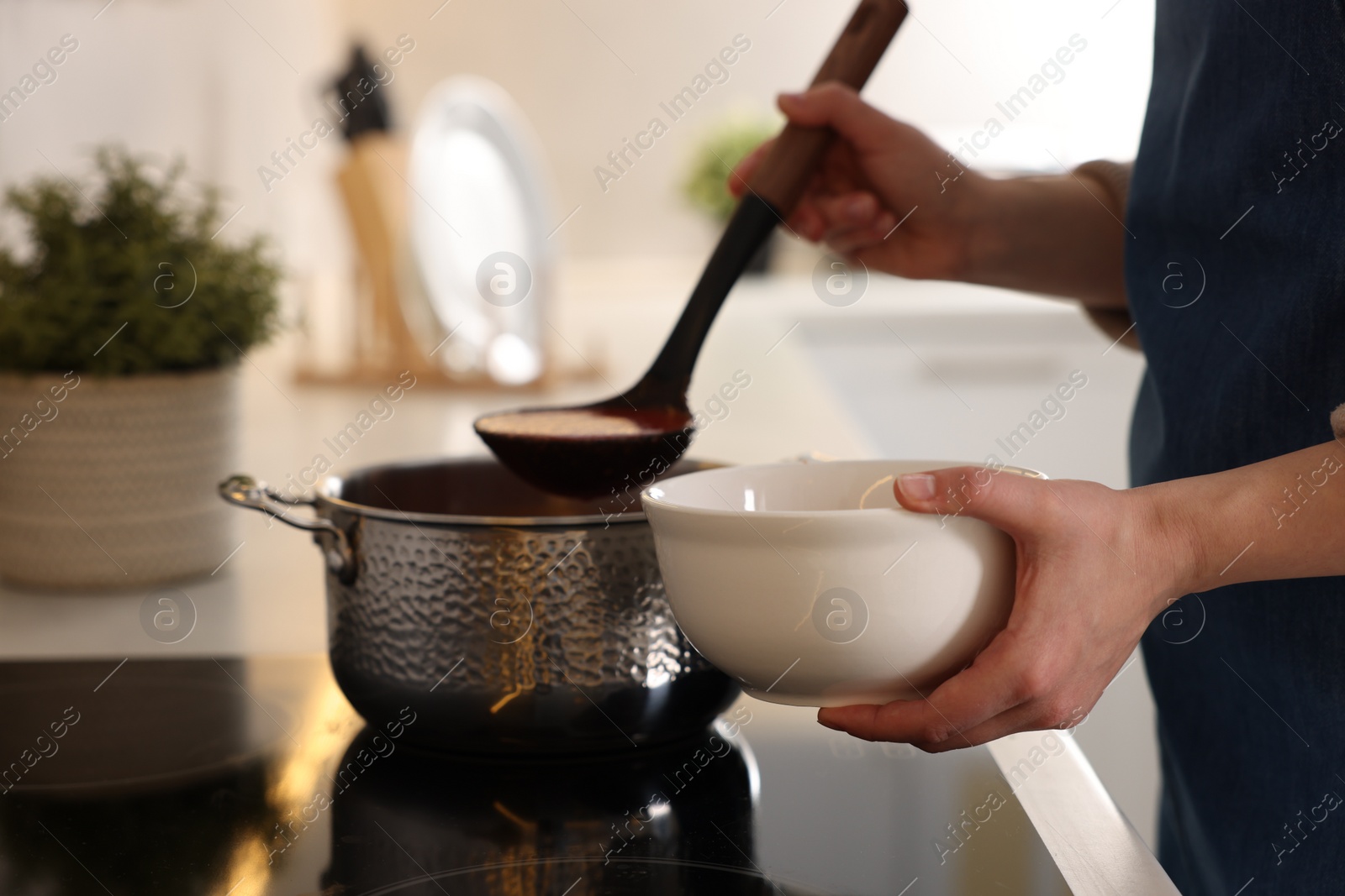 Photo of Woman pouring tasty soup into bowl at countertop in kitchen, closeup