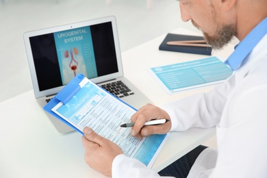 Photo of Mature urologist working at table in hospital