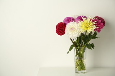 Photo of Bouquet of beautiful Dahlia flowers in vase on white table. Space for text