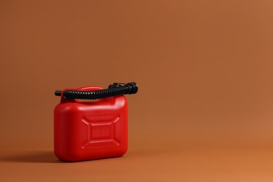 New red plastic canister on brown background. Space for text