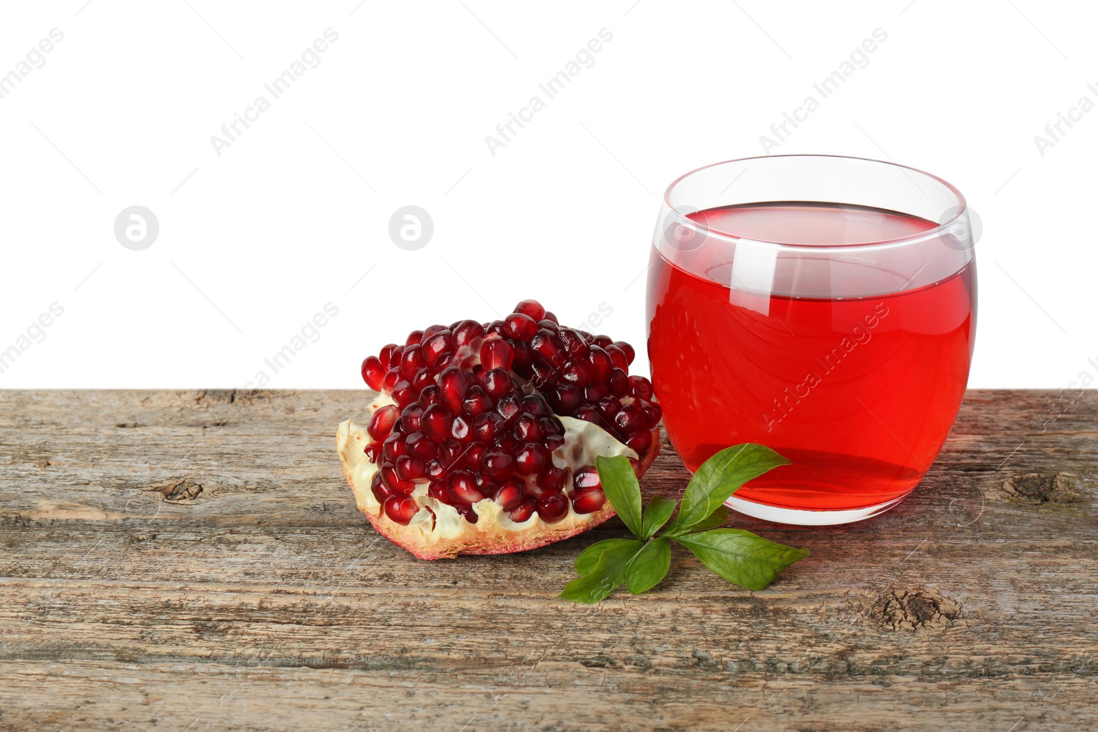 Photo of Refreshing pomegranate juice in glass, leaves and fruit on wooden table against white background