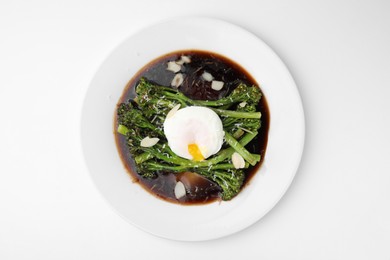 Photo of Tasty cooked broccolini with poached egg, almonds and sauce on white background, top view
