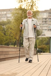 Photo of Senior man performing Nordic walking outdoors, low angle view