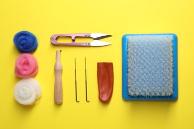 Photo of Flat lay composition with wool and needle felting tools on yellow background