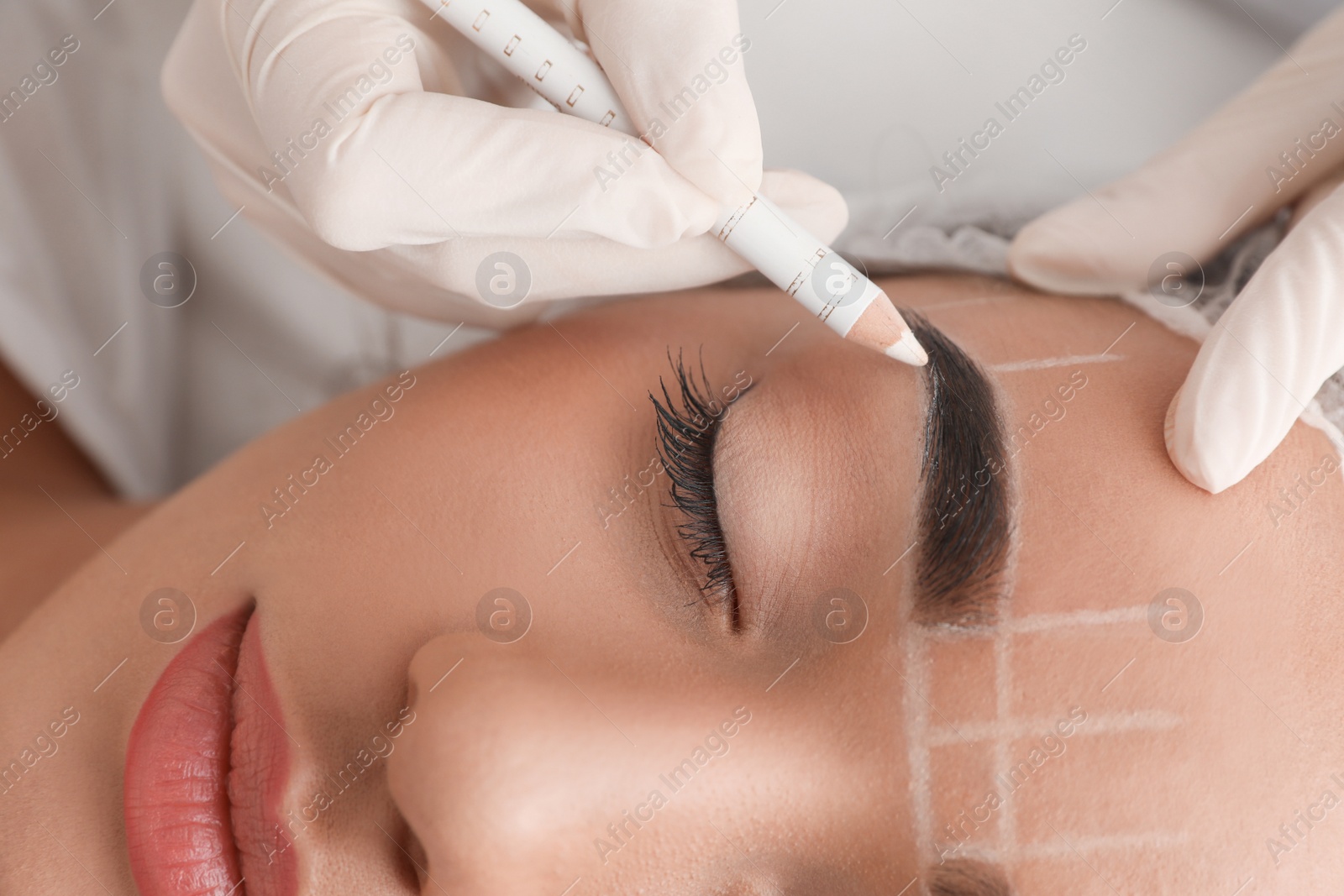 Photo of Young woman getting prepared for procedure of permanent eyebrow makeup in tattoo salon, closeup