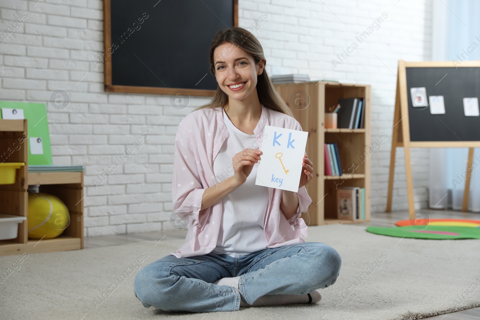 Photo of Happy female English teacher giving lesson in elementary school