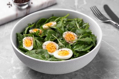 Photo of Delicious salad with boiled eggs and herbs in bowl on light grey marble table, closeup