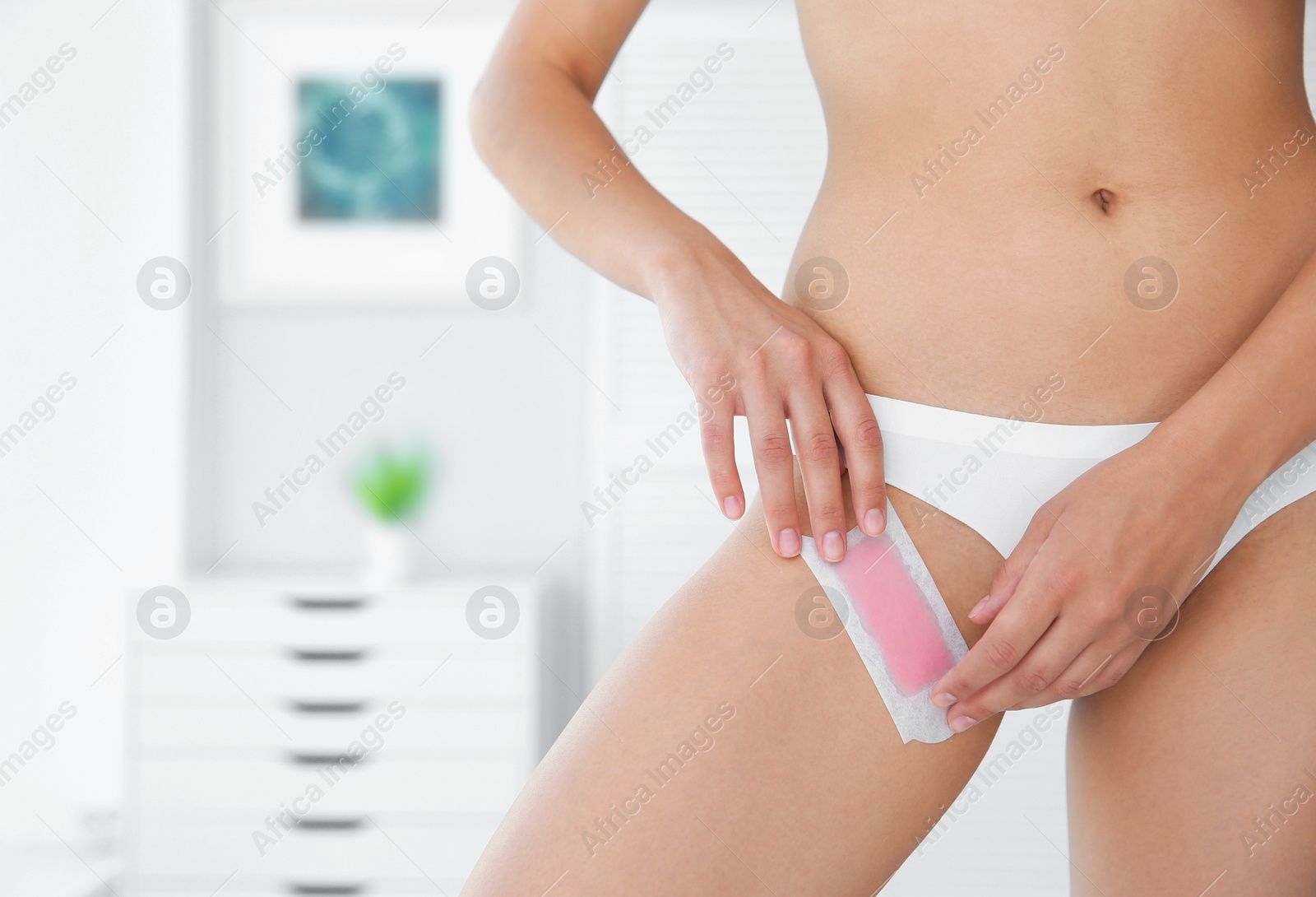 Photo of Sexy young woman waxing bikini area indoors