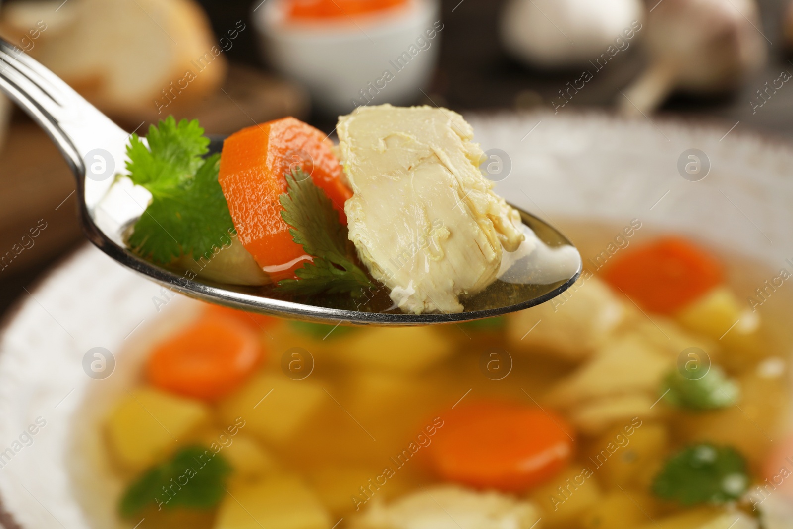 Photo of Spoon with fresh homemade chicken soup on blurred background, closeup