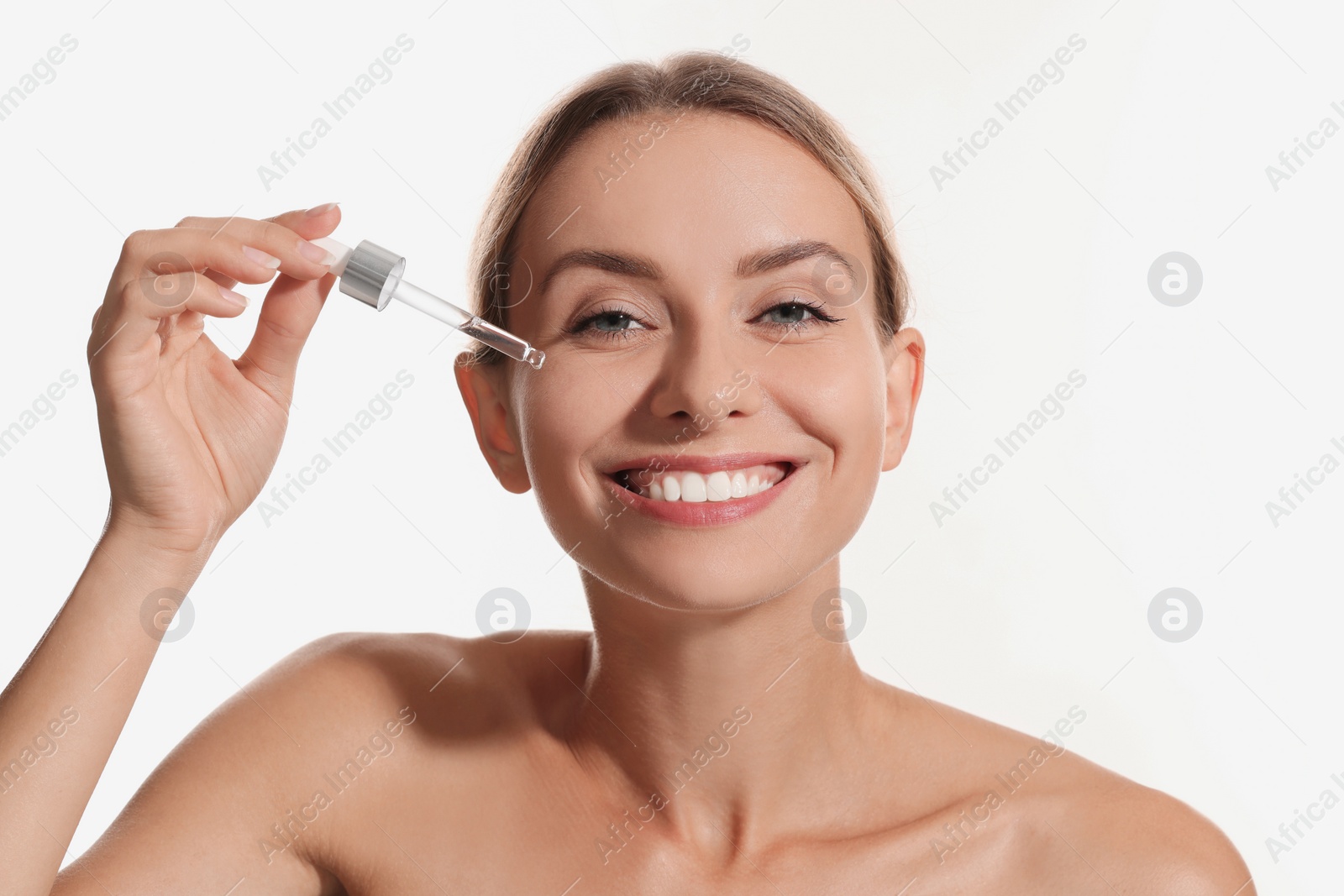 Photo of Beautiful woman applying cosmetic serum onto her face on white background