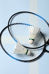 Feather badminton shuttlecocks and rackets on light blue background