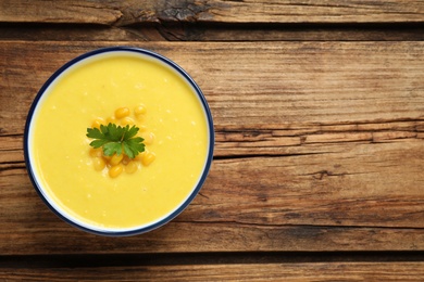 Delicious creamy corn soup on wooden table, top view. Space for text