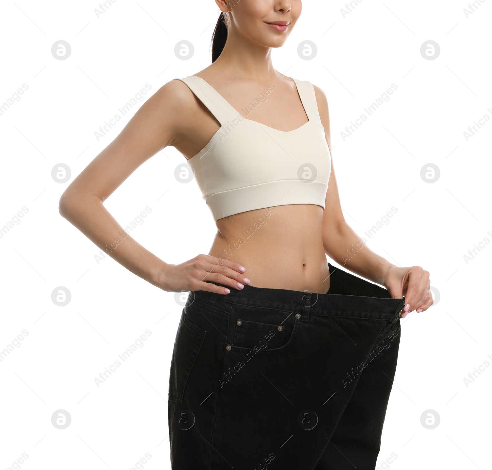 Photo of Young woman wearing big jeans after weight loss on white background, closeup