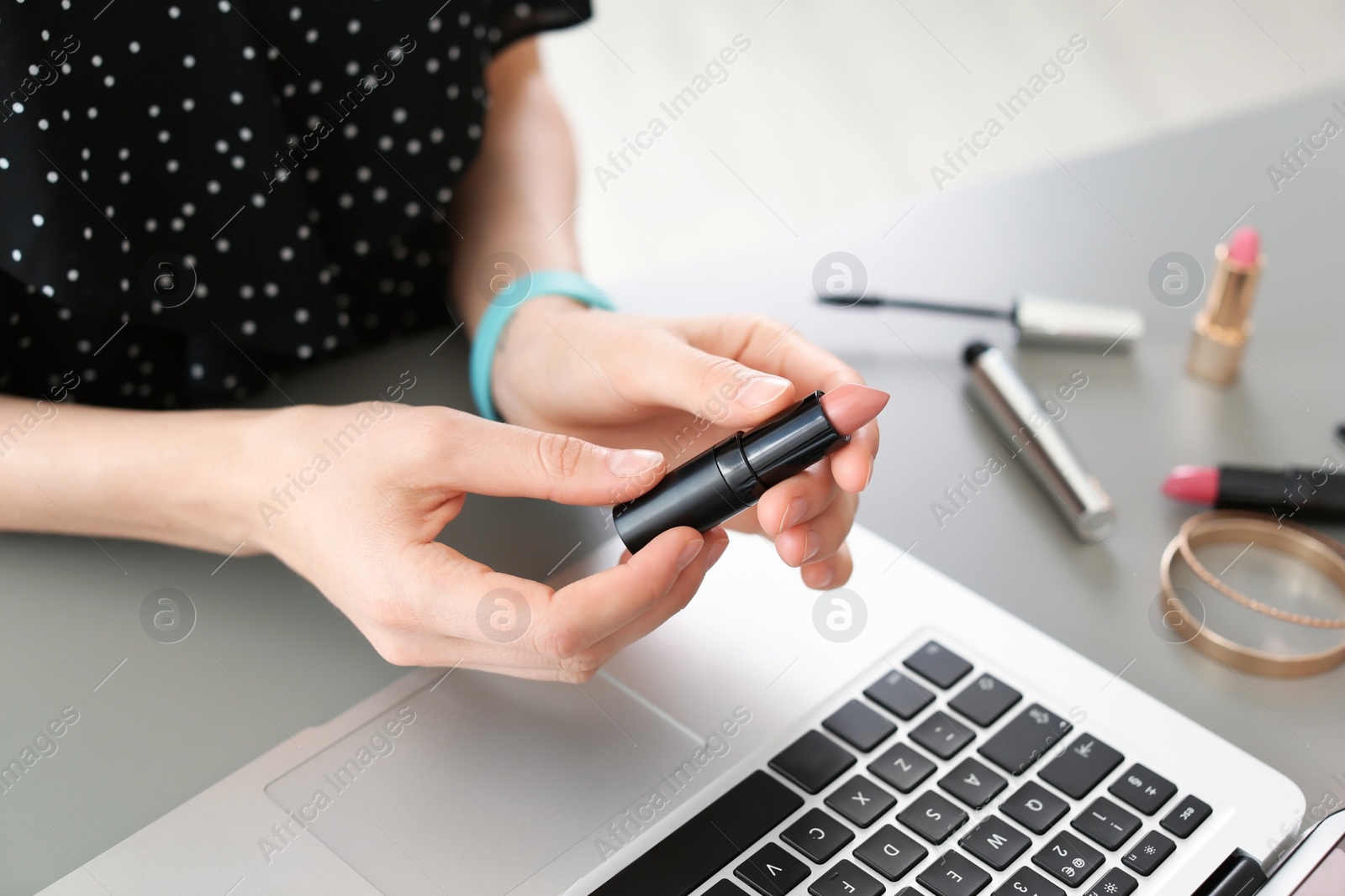 Photo of Young woman with makeup product using laptop at table. Beauty blogger