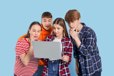 Photo of Group of teenagers using laptop on light blue background