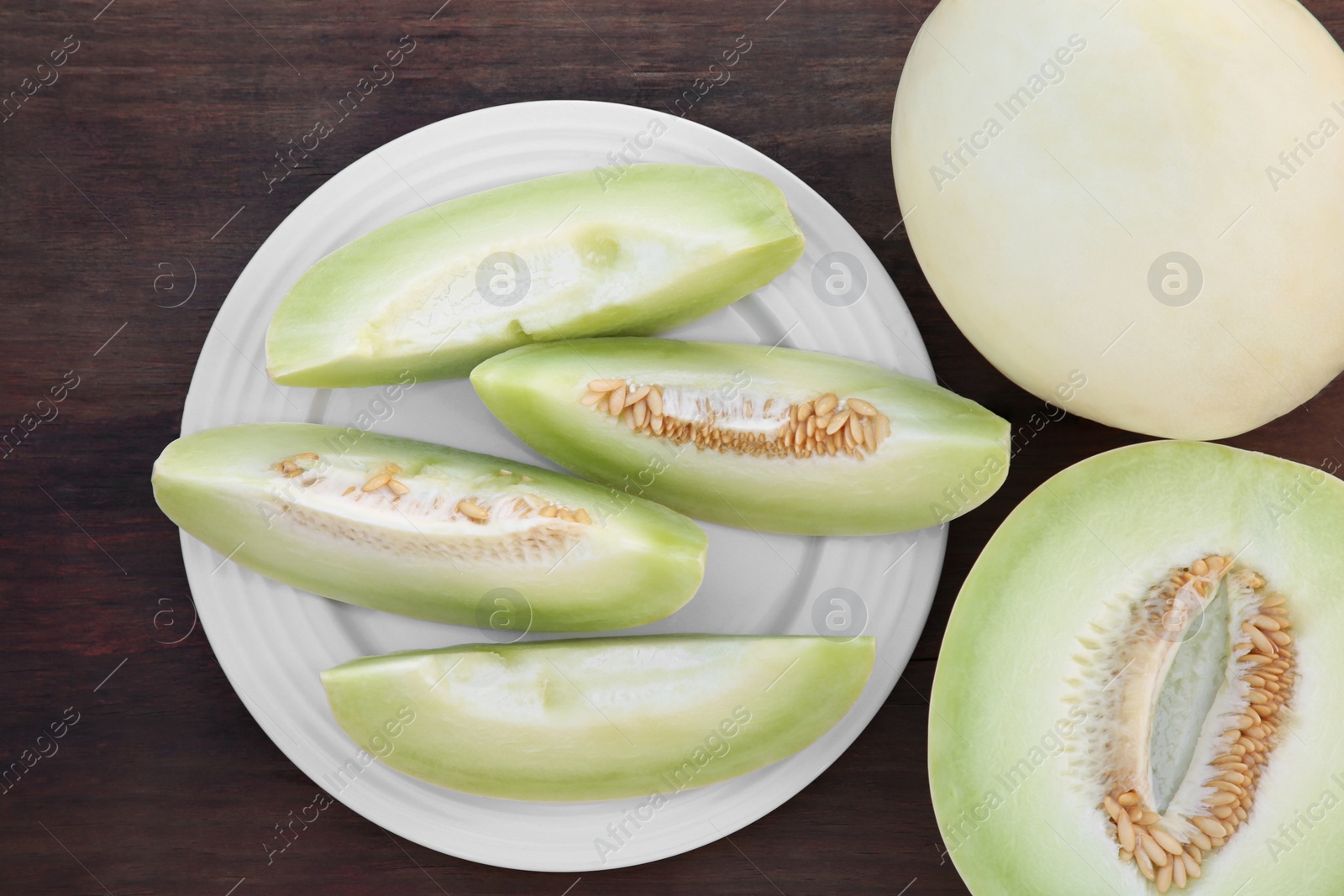 Photo of Tasty whole and cut ripe melons on wooden table, flat lay