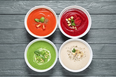 Various soups in bowls on wooden background, top view. Healthy food