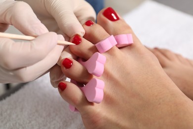 Pedicurist working with client`s toenails in beauty salon, closeup