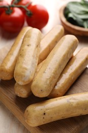 Photo of Raw vegan sausages on wooden board, closeup