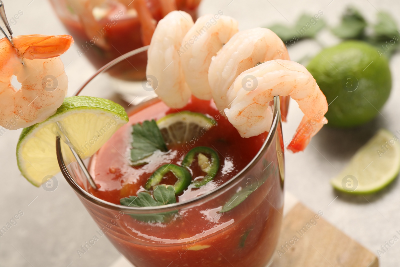 Photo of Tasty shrimp cocktail with sauce in glass and lime on light table, closeup
