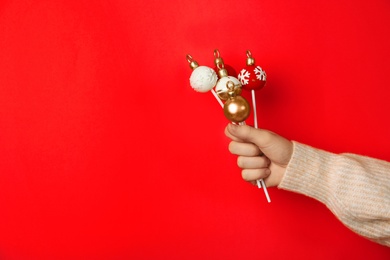 Photo of Woman holding delicious Christmas themed cake pops against pink background, closeup. Space for text
