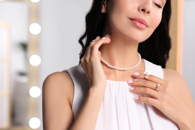 Photo of Young woman wearing elegant pearl jewelry indoors, closeup