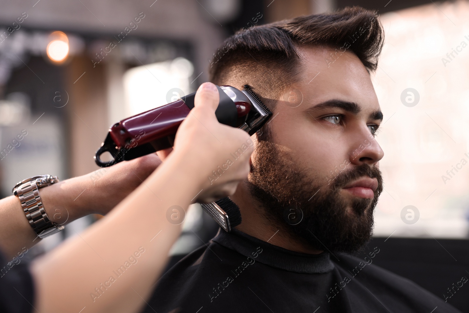 Photo of Professional hairdresser working with client in barbershop